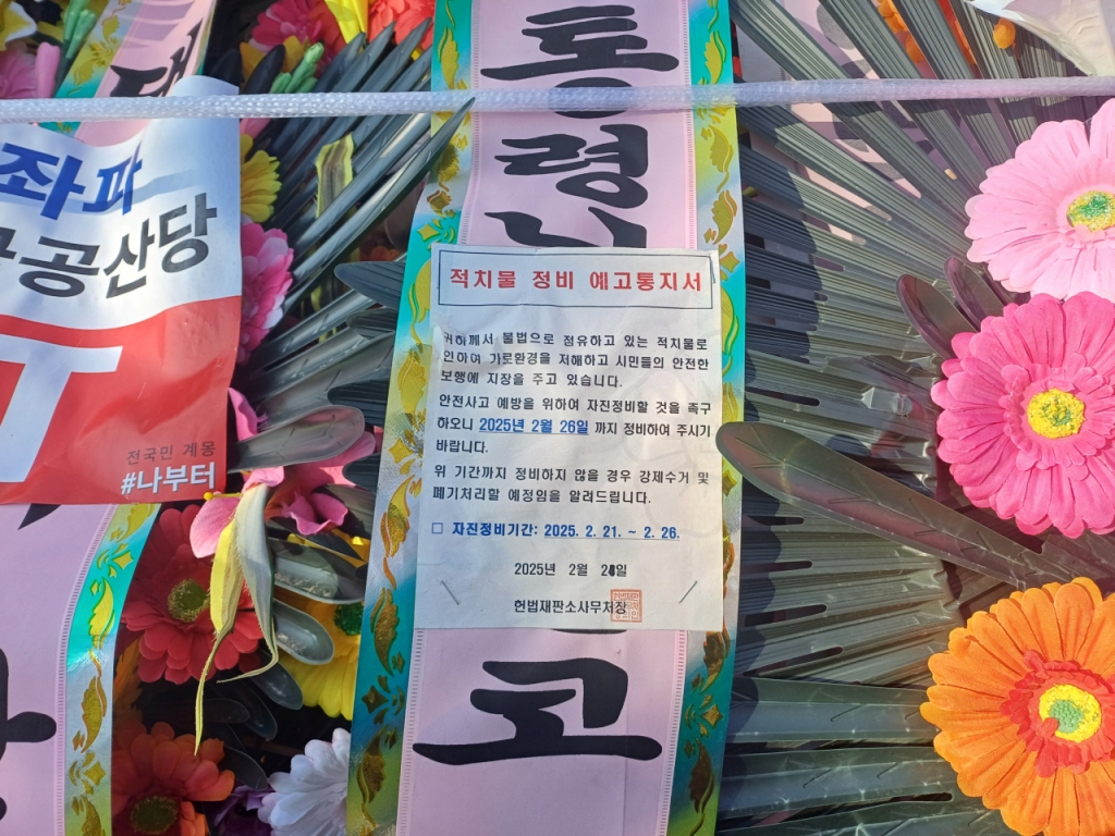 화환들에 붙어있는 '적치물 예고 정비통지서' 에는 지난달 26일까지 자진정비가 되지 않으면 폐기처리하겠다는 내용이 담겼다. /사진=오석진 기자.