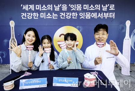 필립스 소닉케어가 ‘세계 미소의 날’을 맞이해 2일 서울 중구 한국은행 앞 분수 광장에서 대한구강보건협회와 함께 건강한 잇몸 미소를 위한 올바른 양치 습관을 알리는 행사를 진행했다.  박용덕 대한구강보건협회 회장(오른쪽 첫 번째)과 모델들이 잇몸 미소를 지으며 올바른 양치법을 소개하고 있다./사진=필립스코리아, 뉴스1