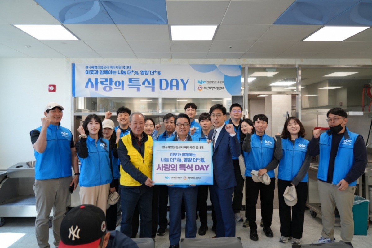 특식 배식에 앞서 부산희망드림센터 식당 내에서 안병길 해진공 사장(판넬을 들고 있는 가운데), 김성진 부산희망드림센터 센터장 그리고 해진공 바다사랑 봉사대원과 함께 기념촬영을 하고 있다./사진=해진공 제공