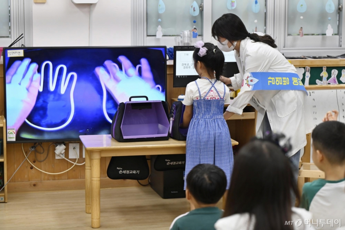 [광주=뉴시스] 박기웅 기자 = 광주 북구보건소 주최로 18일 북구청어린이집에서 열린 여름철 식중독 예방을 위한 '올바른 손씻기 교실에서 감염병관리팀 직원들이 아이들에게 뷰박스를 이용해 손을 씻기 전과 후 청결상태를 보여주고 있다. 2024.07.18. pboxer@newsis.com /사진=박기웅