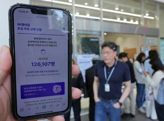 해킹 공격으로 가입자 유심 정보가 탈취된 SK텔레콤이 가입자 유심 무상 교체를 시작한 28일 오전 서울 종로구 T월드 매장 앞에서 직원들의 안내를 받아 온라인 예약을 하고 있다. /사진=뉴스1