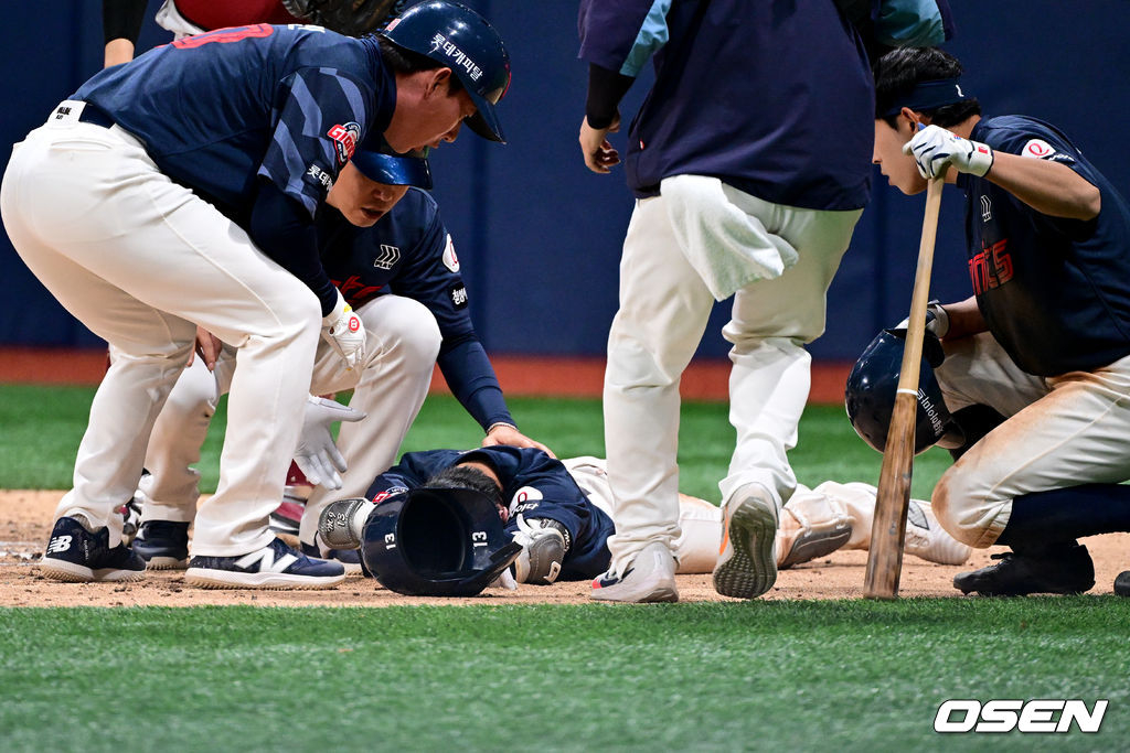 롯데 코칭스태프들이 쓰러진 전민재(가운데)의 몸 상태를 확인하고 있다.