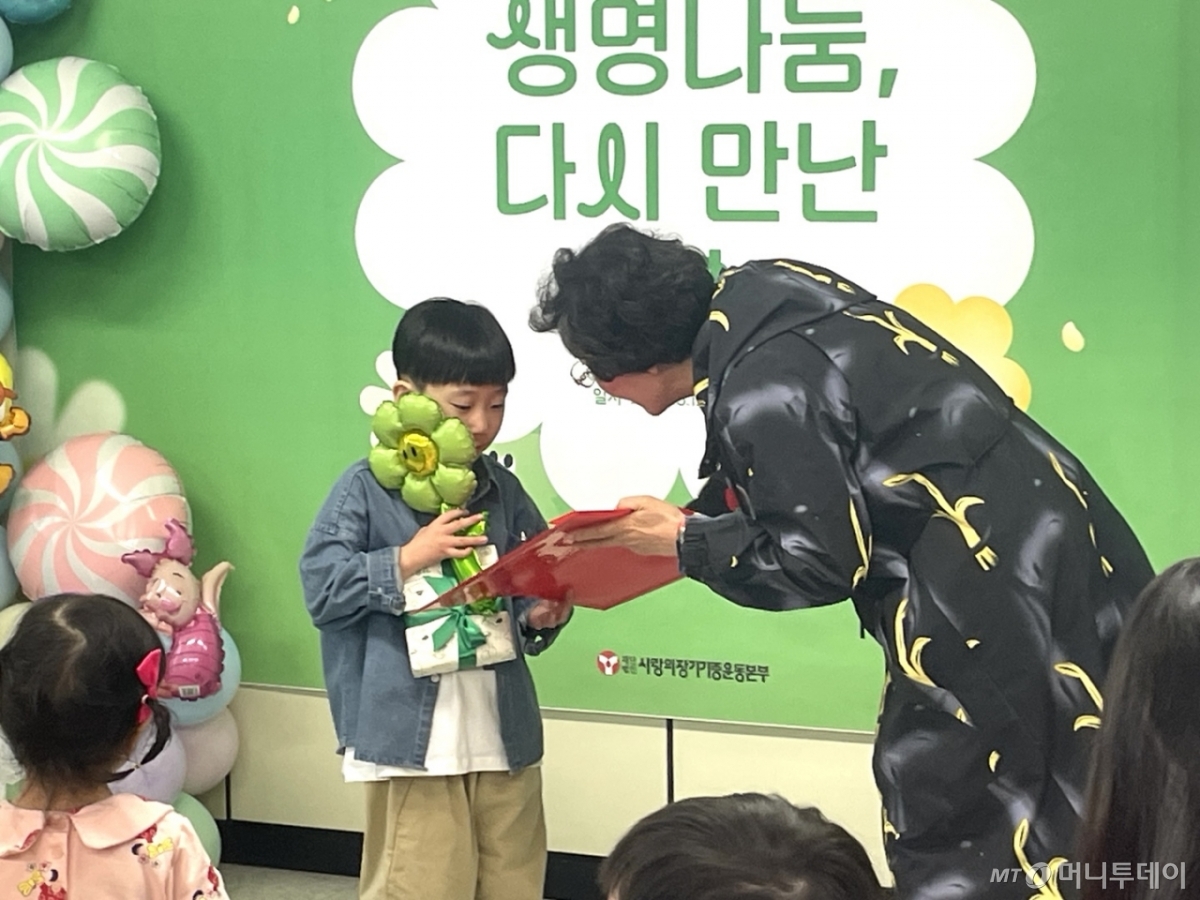 1일 낮 12시 서울 서대문구 사랑의장기기증운동본부에서 장기기증인 유가족이 심장이식인 어린이 강윤호군(9)에게 어린이날 선물을 건네고 있다./사진=이현수 기자.