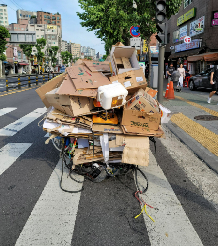 끄는 사람이 보이지 않을 정도로 높이 쌓인 폐지 리어카./사진=녹색병원 제공
