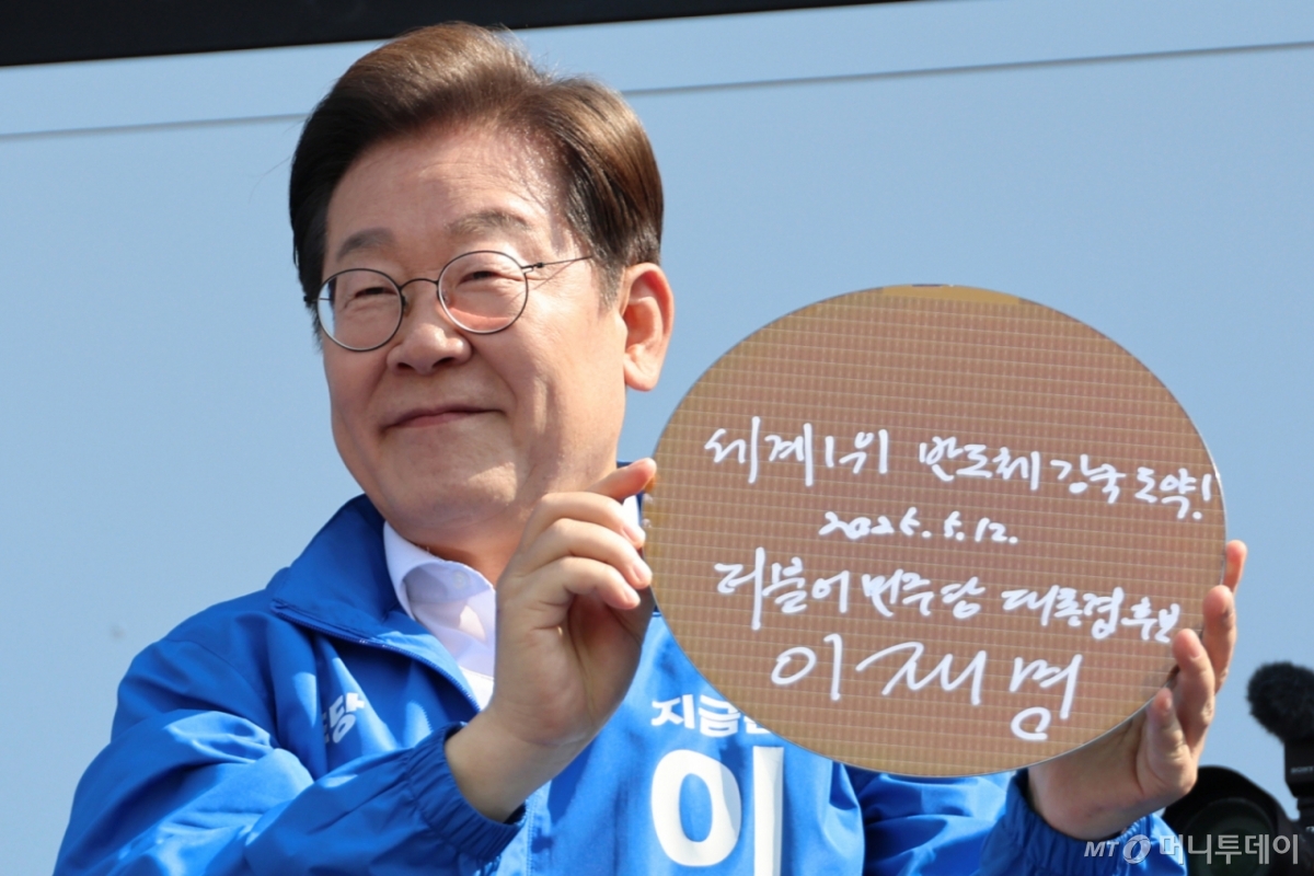(화성=뉴스1) 안은나 기자 = 이재명 더불어민주당 대통령 후보가 제21대 대통령 선거 공식 선거운동 첫날인 12일 오후 경기 화성시 동탄 센트럴파크 음악분수중앙광장에서 '세계1위! 반도체 강국 도약!'이라고 쓴 반도체 웨이퍼를 들어 보이고 있다. (공동취재) 2025.5.12/뉴스1 Copyright © 뉴스1. All rights reserved. 무단 전재 및 재배포, AI학습 이용 금지. /사진=(화성=뉴스1) 안은나 기자