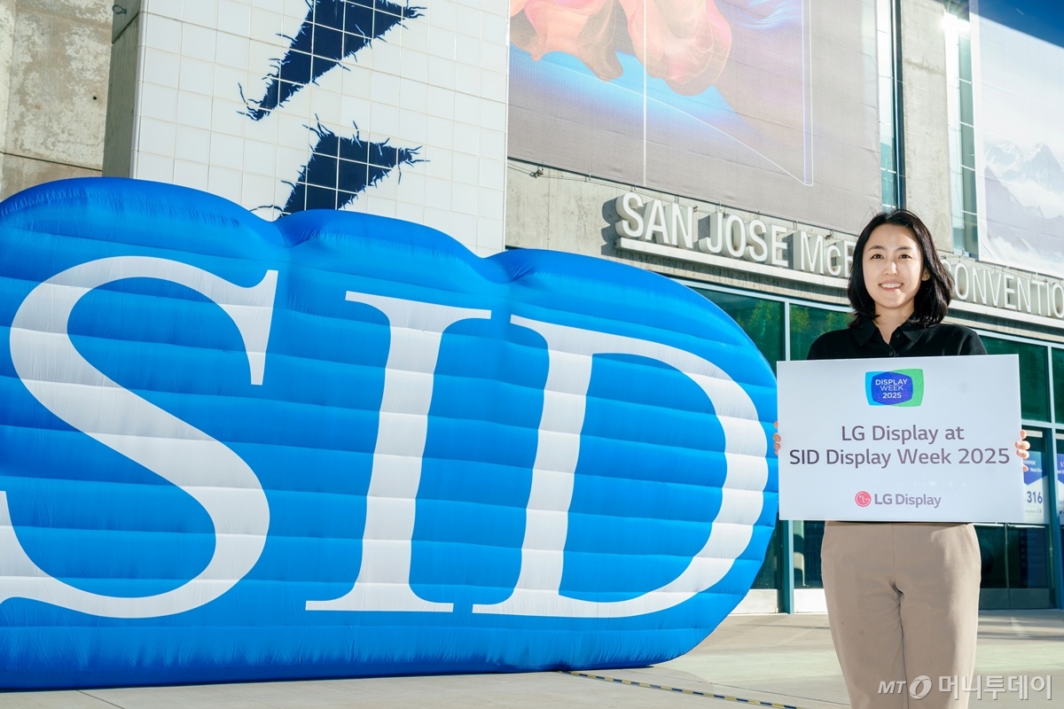 LG디스플레이 직원이 12일(현지시간) 세계 최대 디스플레이 전시회 'SID 2025'가 열리는 미국 새너제이 맥에너리컨벤션센터 앞에서 참가 소식을 알리고 있다./사진=LG디스플레이