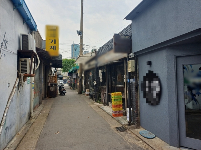 지난 25일 오전 서울 영등포구 문래동 골목에 문을 열지 않은 철공소가 있다. 맞은편에 술집과 카페가 늘어선 모습. /사진=오석진 기자.