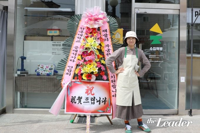 ▲청년몰 가동 104호에 입점한 수집책방의 이수빈 대표. 개업 이틀째를 맞은 자신만의 첫 매장 앞에서 포즈를 취하고 있다./사진=최현승 기자