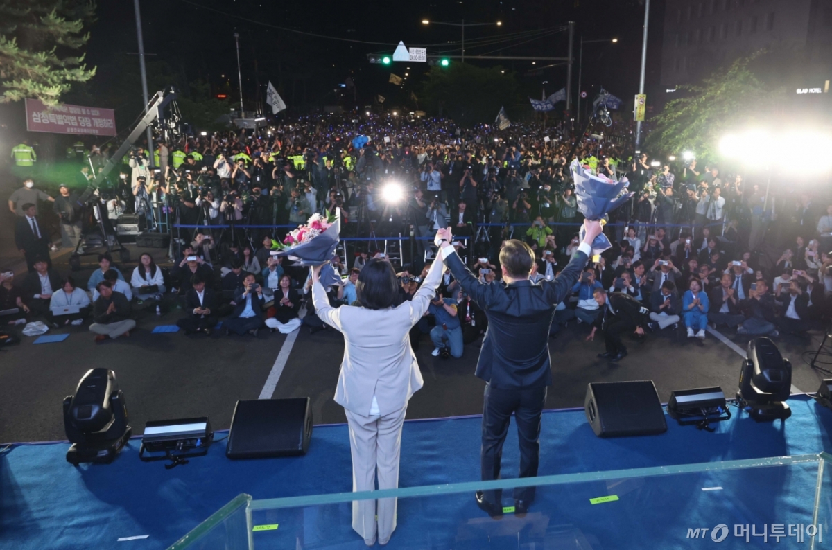 [서울=뉴시스] 조성우 기자 = 이재명 대통령과 김혜경 여사가 4일 오전 서울 여의도 국회 앞에서 열린 국민 개표방송 행사에서 꽃다발을 받은 뒤 시민들을 향해 인사하고 있다. (공동취재) 2025.06.04. 