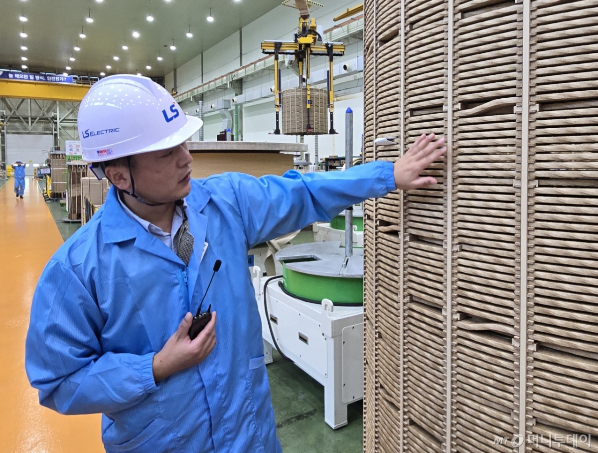 권선 작업을 마친 나무로 감싼 구리선. HVDC 변환용 변압기(CTR)을 생산하기 위해서는 이 구리선에서 수분을 빼내는 작업을 최소 12번 이상 진행해야 한다. 해당 과정을 설명하는 최형석 LS일렉트릭 부산사업장 제조팀장./사진=최지은 기자
