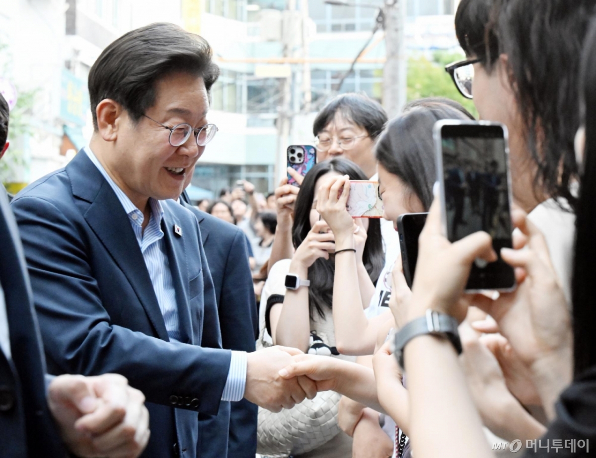  이재명 대통령이 11일 외식 행사를 위해 서울 종로구 한 식당으로 걸어서 이동하던 중 시민들과 인사하고 있다.  이 대통령은 SNS에 식사 계획을 알리며 "이처럼 어려운 시기에 21일부터 시행되는 민생회복 소비쿠폰 정책이 내수 진작과 지역 경제 활성화에 활력을 불어넣길 기대한다"고 밝혔다. (대통령실통신사진기자단) 2025.07.11. 