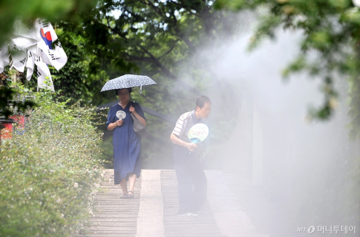 [대구=뉴시스] 이무열 기자 = 폭염이 연일 계속된 23일 대구 중구 청라언덕에 설치된 쿨링포그 아래로 시민들이 손 선풍기와 부채를 들고 이동하고 있다. 2025.07.23. lmy@newsis.com /사진=이무열
