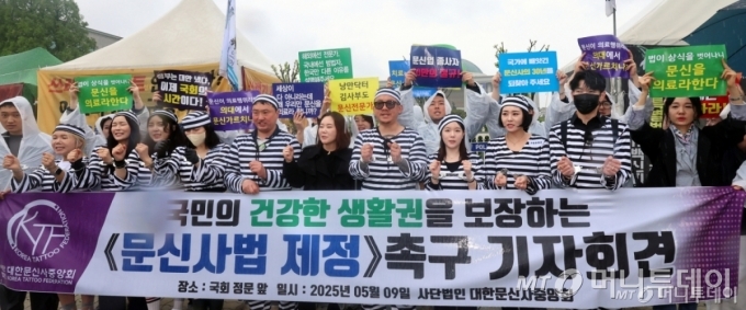 (서울=뉴스1) 황기선 기자 = 대한문신사중앙회 회원들이 9일 오후 서울 영등포구 여의도 국회 앞에서 '문신사법 제정 촉구를 위한 기자회견'을 진행하고 있다.  이날 회원들은 기자회견을 통해 문신업 종사자들의 직업적 권리 및 생존권 보장을 위한 법안 통과와 문신사 양성화를 촉구했다. 2025.5.9/뉴스1  Copyright © 뉴스1. All rights reserved. 무단 전재 및 재배포,  AI학습 이용 금지. /사진=(서울=뉴스1) 황기선 기자