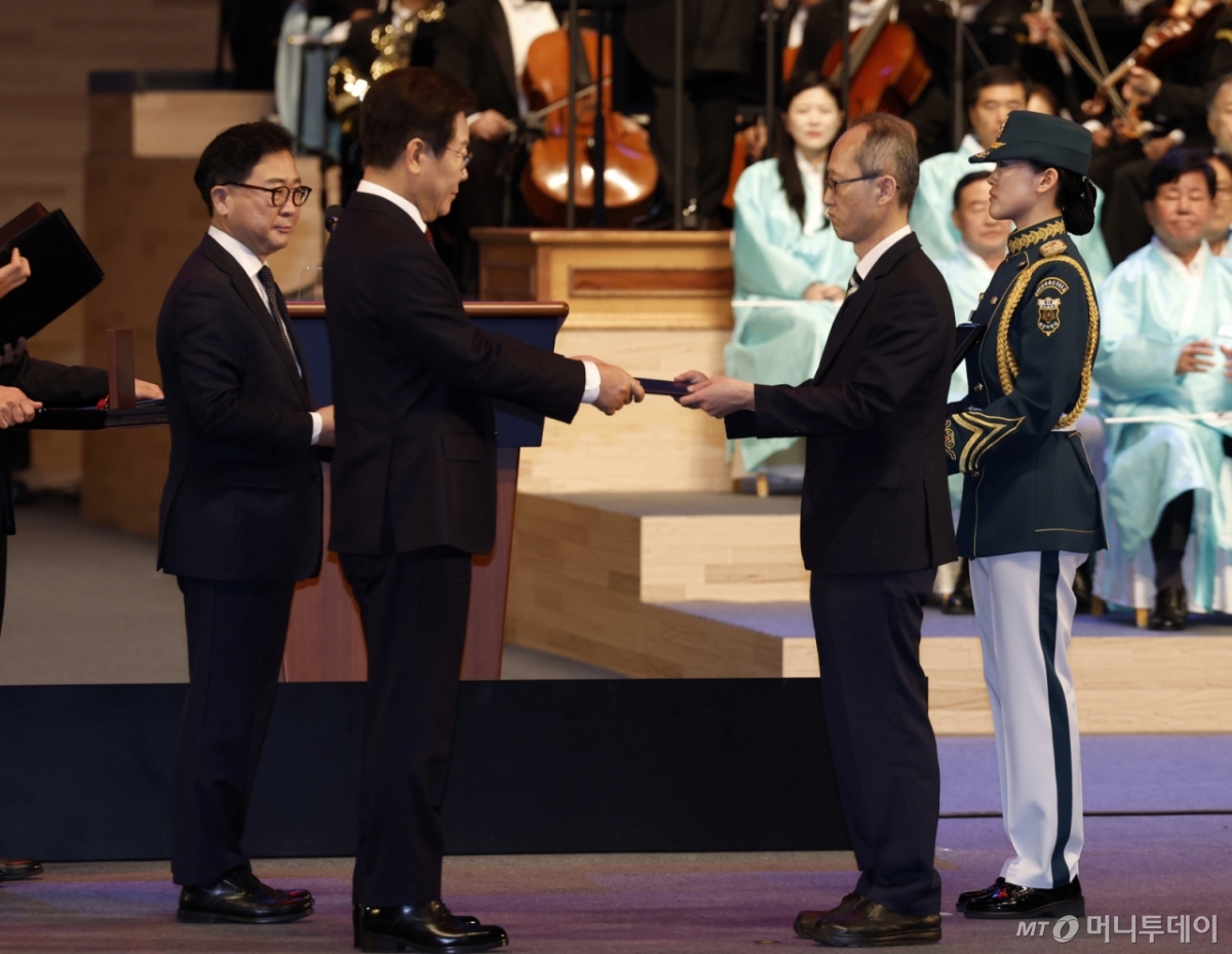 [서울=뉴시스] 최동준 기자 = 이재명 대통령이 15일 서울 종로구 세종문화회관에서 열린 제80주년 광복절 경축식에서 고(故) 이은숙 선생의 외손자 김종민 씨에게 건국훈장 애족장 훈장증을 전달하고 있다. 2025.08.15. photocdj@newsis.com /사진=최동준