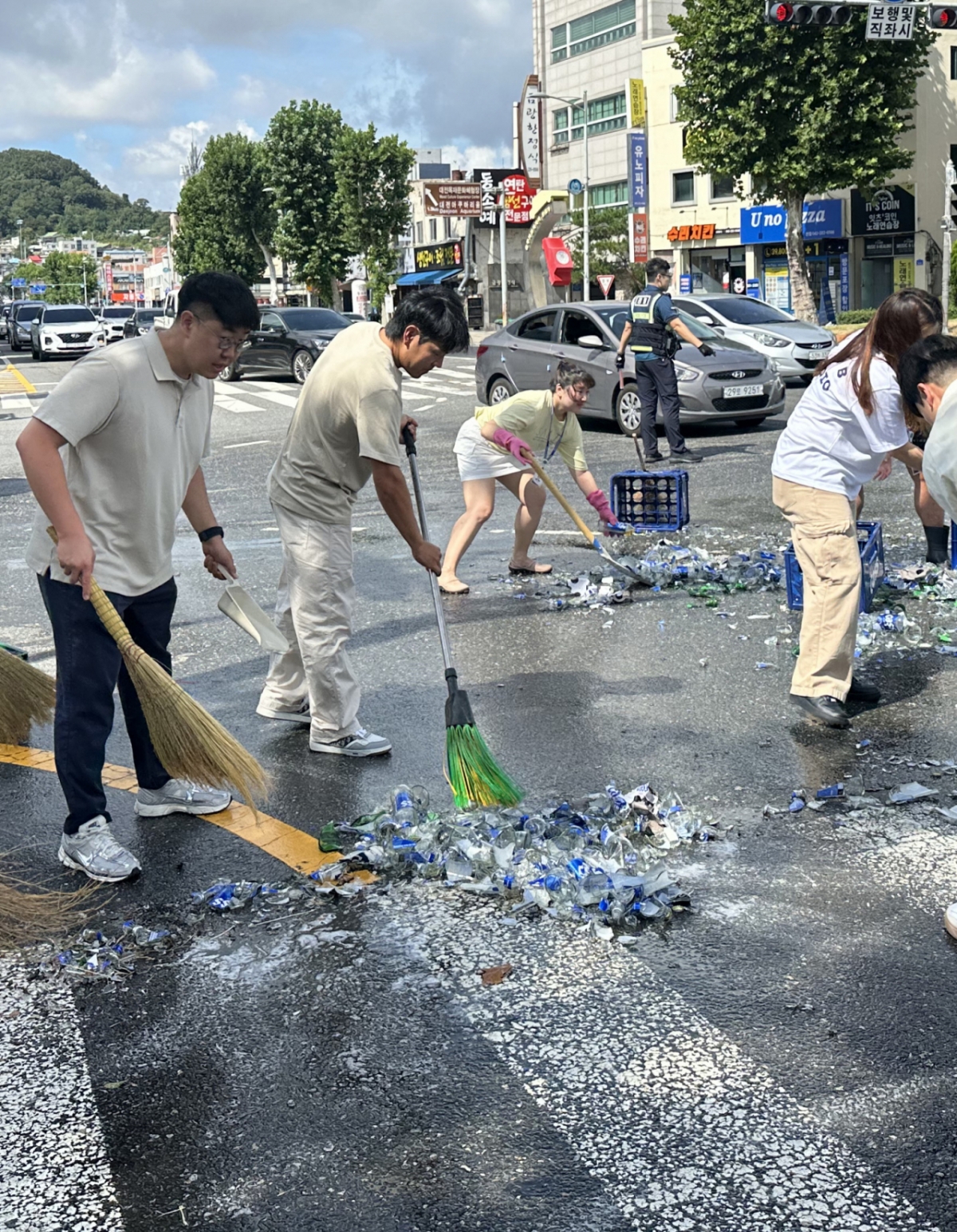 29일 오전 대전 중구 대사동 충무로네거리에서 한 트럭에 실린 맥주병 상자 20여개가 도로 위로 쏟아져 맥주병 약 400개가 깨졌다. 사고를 목격한 대전시체육회 직원들과 시민들이 도로를 치우는 모습./사진=뉴스1(대전시체육회 제공)