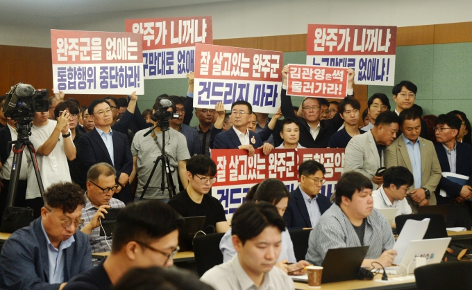 ▲지난 7월 21일 완주군의회 의원들을 비롯한 완주·전주 통합을 반대하는 군민들이 전북 전주시 전북특별자치도청 기자회견장에서 열린 완주-전주 통합과 관련한 기자회견을 청취하며 손피켓을 들고 있다./사진=뉴시스