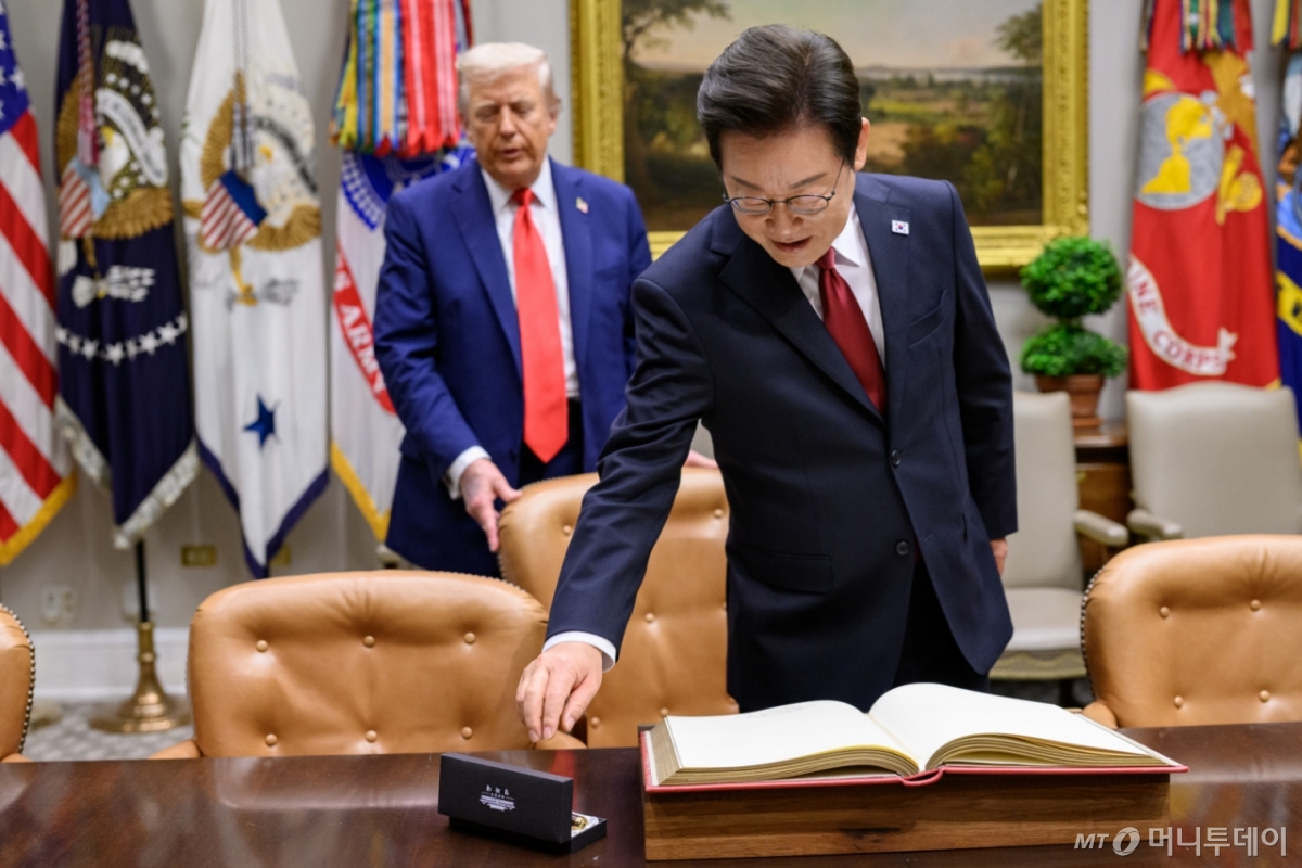 (워싱턴=뉴스1) 류정민 특파원 = 지난 8월 25일(현지시간) 이재명 대통령이 한미정상회담에 앞서 미 백악관 루즈벨트룸에서 방명록에 서명하려고 펜을 잡으려는 순간 도널드 트럼프 미국 대통령이 뒤에서 의자를 당겨 주고 있다. 2025.08.31(백악관 제공. 재판매 및 DB금지)  Copyright © 뉴스1. All rights reserved. 무단 전재 및 재배포,  AI학습 이용 금지. /사진=(워싱턴=뉴스1) 류정민 특파원