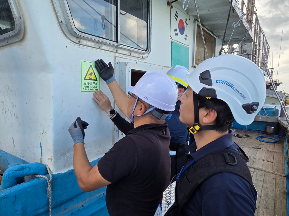 공단이 식별성과 내구성을 강화해 현장에 보급 중인 어선 안전·보건 표지. 밤에도 형광으로 볼 수 있는 표지로 미끄러지기 쉬운 갑판 위 넘어질 위험이 있는 곳에 감독관과 선장이 함께 표시를 붙이고 있다./사진=목포 공동취재단. 
