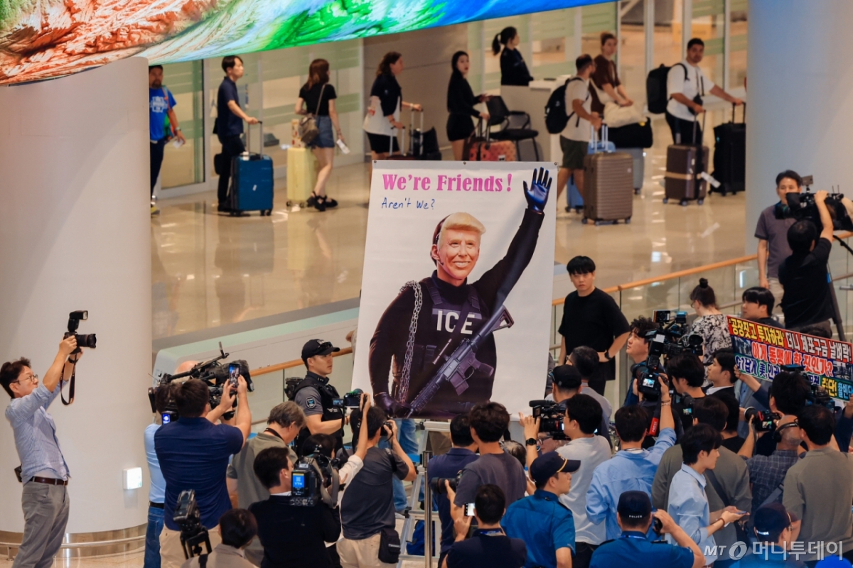 미국 이민당국에 의해 체포·구금됐다 풀려난 한국인 316명이 탑승한 전세기가 지난 12일 인천국제공항 제2터미널에 도착한 당시 모습. 도널드 트럼프 미국 대통령을 그린 현수막에 '우리는 친구잖아, 그렇지'(We're friends! Aren't we?)라는 문구가 적혀 있다. / 사진=뉴시스