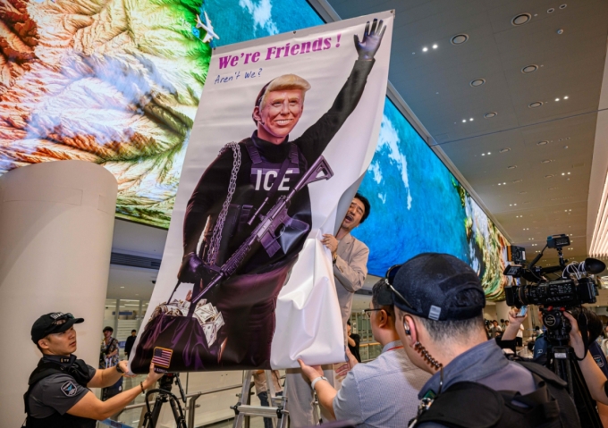 [인천공항=뉴시스] 황준선 기자 = 미국 조지아주 포크스턴 이민세관단속국(ICE) 구금 시설에서 체포·구금됐다 풀려난 한국인 316명이 탑승한 전세기가 12일 인천국제공항 2터미널에 도착한 가운데, 이제석 이제석광고연구소 대표가 공항 입국장에서 트럼프 미국 대통령 얼굴이 담긴 플래카드 퍼포먼스를 펼치고 있다. 