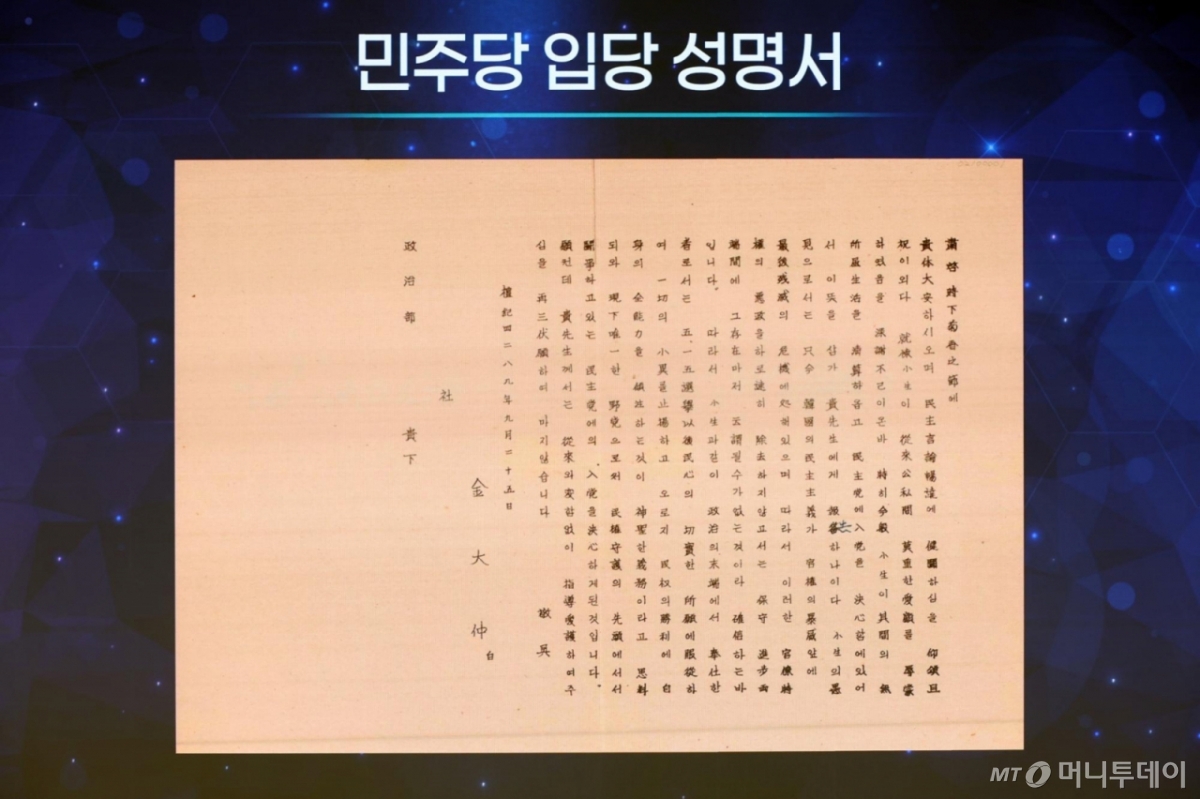 [서울=뉴시스] 고승민 기자 = 정청래 더불어민주당 대표가 19일 서울 여의도 국회 의원회관에서 열린 더불어민주당 창당 70주년 기념식에서 권노갑 김대중재단 이사장에게 김대중 전 대통령의 입당 성명서를 전달받기 전 성명서가 모니터에 송출되고 있다. 2025.09.19. kkssmm99@newsis.com /사진=고승민