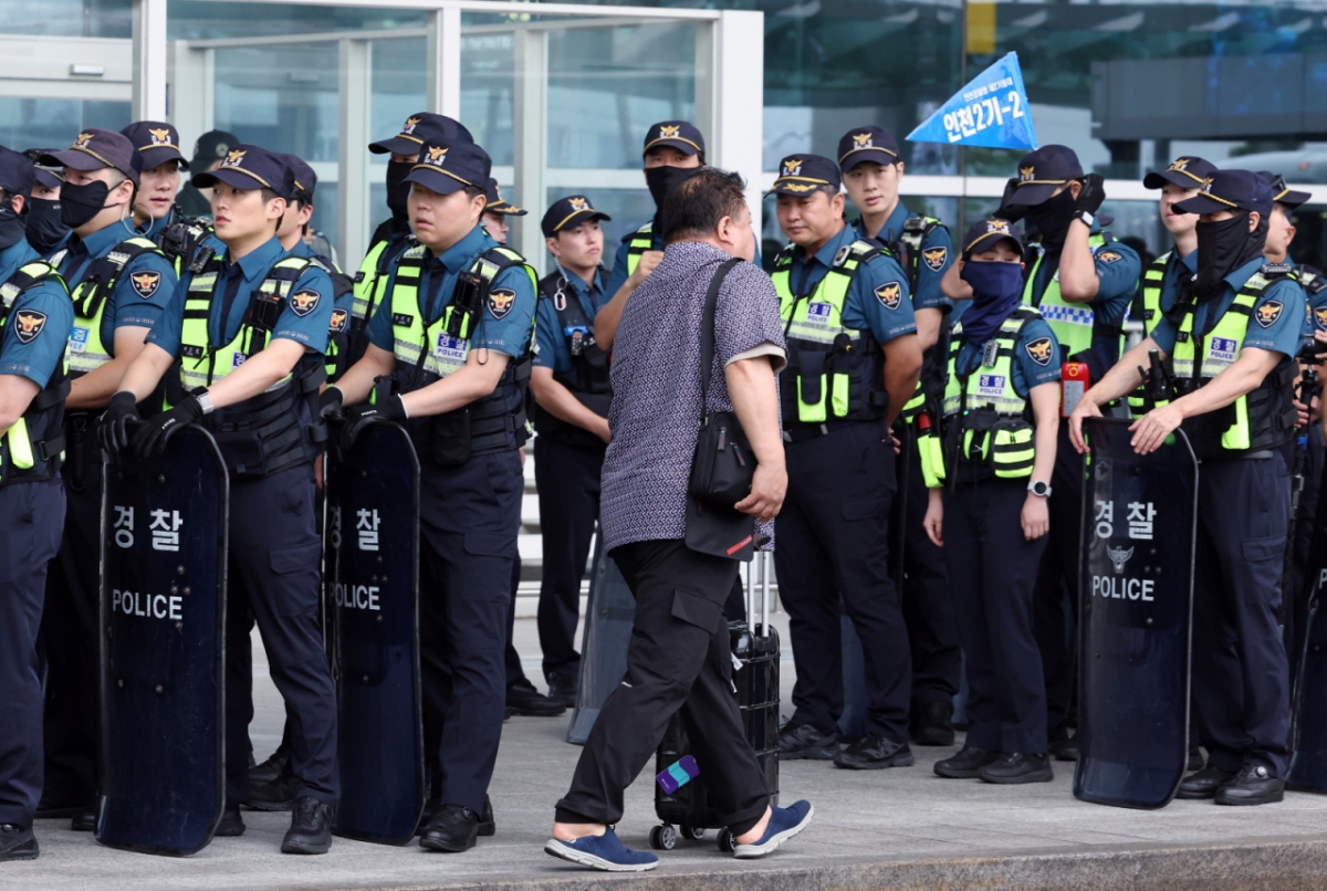 9일 오전 인천국제공항 2터미널에서 열린 민주노총 전국공공운수노조 인천공항지역지부와 전국공항노동조합 등 전국공항노동자연대의 안전한 일터·안전한 공항을 위한 전국공항노동자 총파업 대회 안전 관리를 위해 대기하는 경찰들 옆으로 여행객이 지나고 있다. 사진은 기사와 연관없음/사진=뉴스1