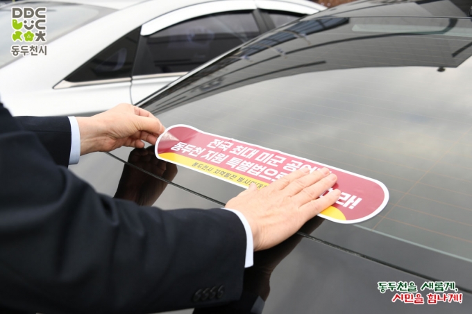 ▲지난해 동두천시 지역발전 범시민대책위원회가 미군 공여지 보상을 요구하는 차량 스티커를 배포하는 캠페인을 벌였다./사진제공=동두천시