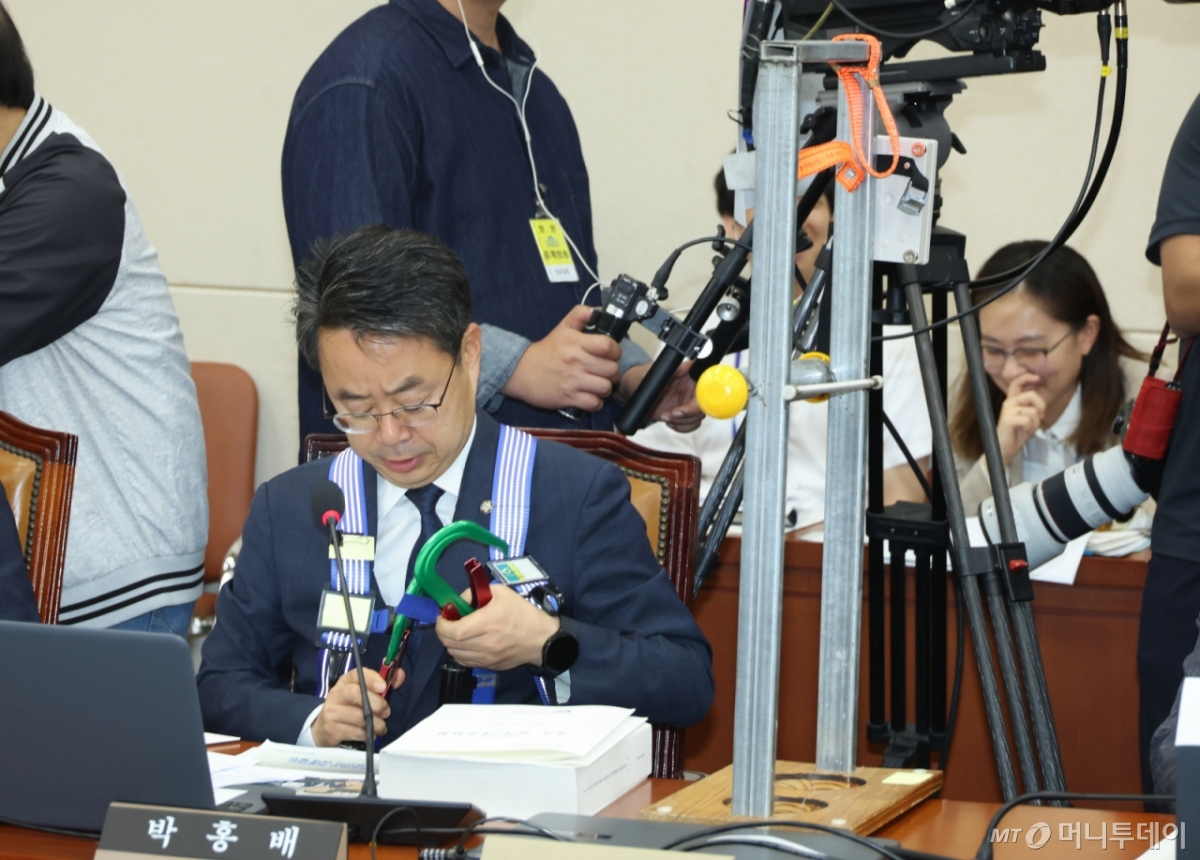 [서울=뉴시스] 고승민 기자 = 박홍배 더불어민주당 의원이 15일 서울 여의도 국회에서 열린 기후에너지환경노동위원회의 고용노동부 등 국정감사에서 하네스 등 산업용 안전장비 관련 질의를 마친 뒤 장비를 거두고 있다. 2025.10.15. kkssmm99@newsis.com /사진=고승민