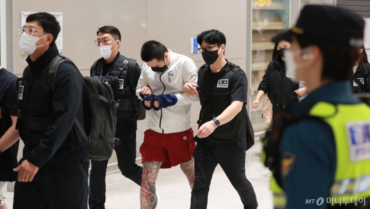 캄보디아에 구금됐다 송환된 한국인들이 지난 18일 오전 인천국제공항을 통해 귀국한 뒤 경찰서로 압송되고 있다. 현지에서 범죄에 가담한 혐의를 받는 이들 중 상당수는 노출된 팔다리가 문신으로 뒤덮여 있었다. /인천국제공항=공동취재단