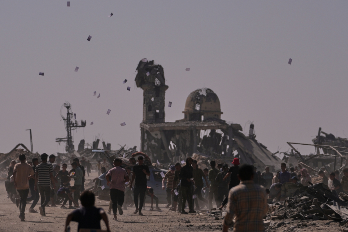 팔레스타인 주민들이 20일(현지 시간) 가자지구 남부 칸유니스에서 이스라엘 드론이 투하한 ‘옐로 라인(이스라엘의 가자지구 내 철수선) 접근 금지 경고' 전단을 받고 있다. /AP=뉴시스