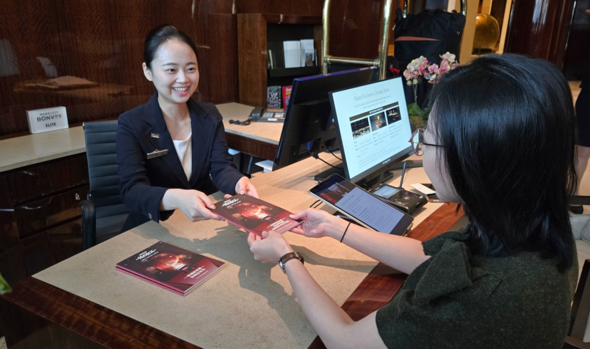 웨스틴 조선 서울에서 직원이 외국인 고객에게 '2025 쓱데이 가이드북'을 전달하며 쓱데이 행사에 대해 안내하고 있다. /사진제공=신세계그룹