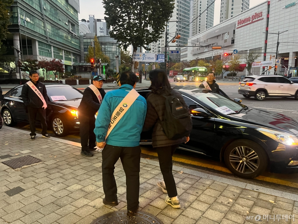 오전 7시쯤 봉사차량에 탑승하는 첫 번째 수험생이 구청관계자와 운전봉사자들의 안내를 받으며 차량으로 이동하고 있다./사진=이정우 기자.