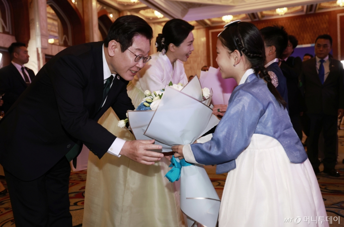 [아부다비=뉴시스] 최동준 기자 = 남아공 G20 정상회의 참석 차 아랍에미리트(UAE)를 국빈 방문한 이재명 대통령과 김혜경 여사가 17일(현지 시간) 아부다비의 한 호텔에서 열린 동포 만찬 간담회에서 화동에게 꽃다발을 받고 있다. 2025.11.18. photocdj@newsis.com /사진=최동준