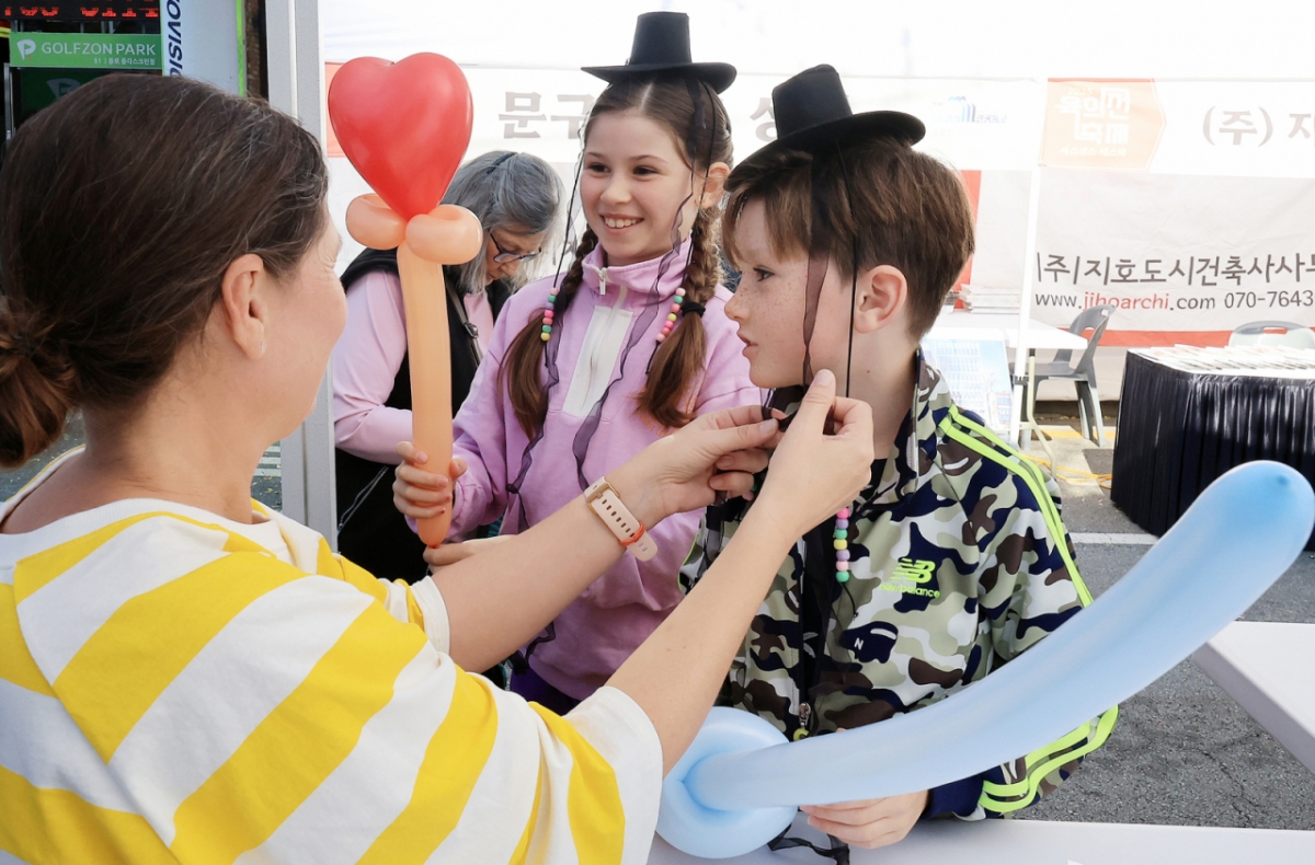 지난 15일 오후 서울 종로구 청계천 장통교 일원에서 열린 '2025 육의전 축제'를 찾은 외국인 어린이들이 직접 만든 갓을 써보며 환하게 웃고 있다. /사진 = 뉴스1