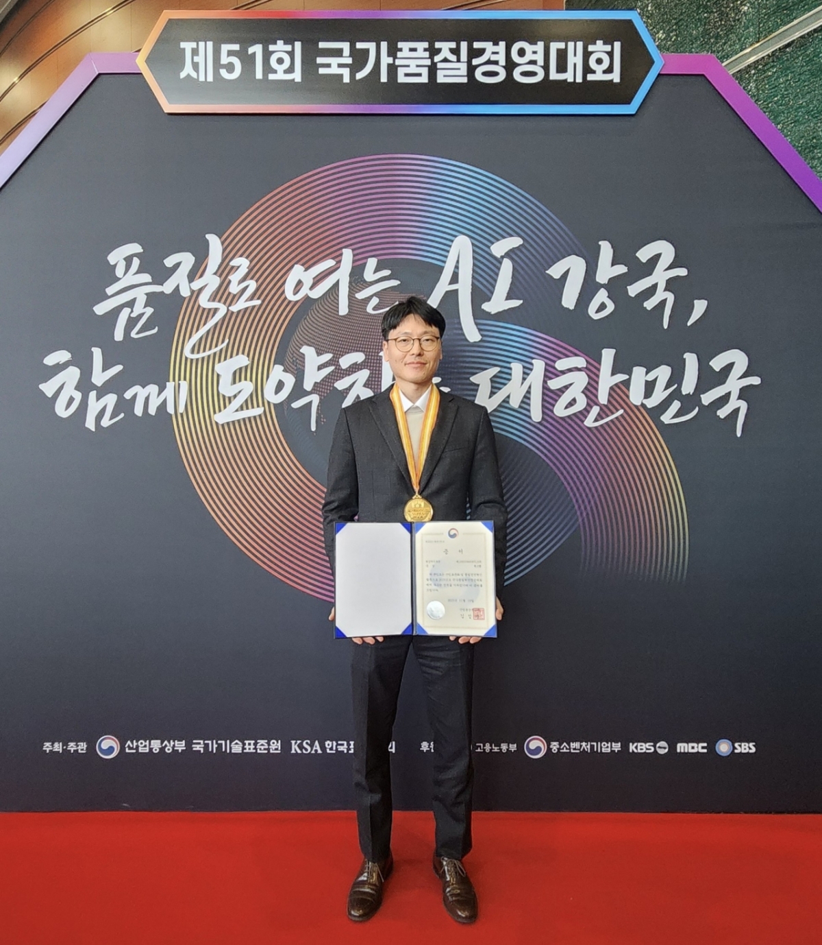 김지완 SNT다이내믹스 원스텝 분임조장(생산1팀 생산3파트장)이 국가품질경영대회에서 우수 품질분임조 금상을 수상하고 기념촬영을 하고 있다./사진제공=SNT다이내믹스