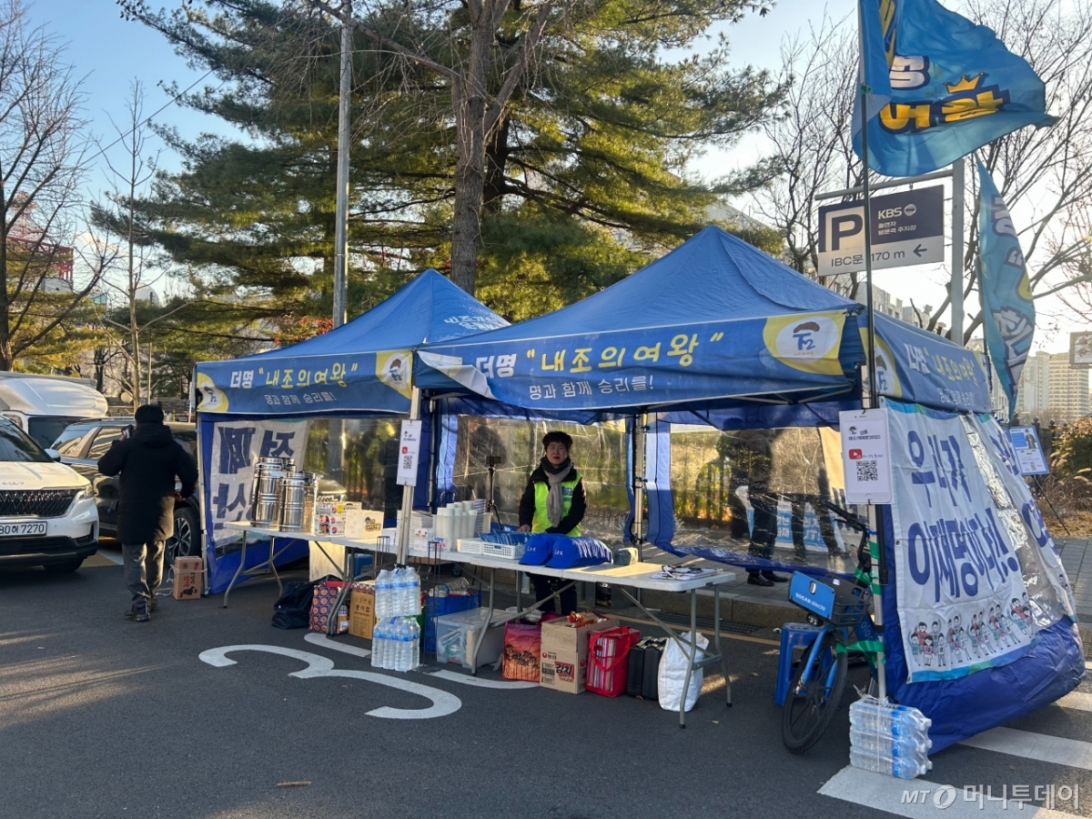 60대 여성 박미희씨가 부스 안에서 이재명 대통령 굿즈를 정리하고 있는 모습. 박씨는 지난해 12월3일 계엄 당시에도 3박4일 동안 국회 앞을 지켰다./사진=김지현 기자.