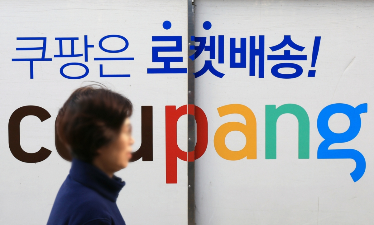 지난 2일 한 시민이 서울의 쿠팡 물류센터 앞에 주차된 쿠팡카 앞을 지나는 모습./사진-뉴스1.