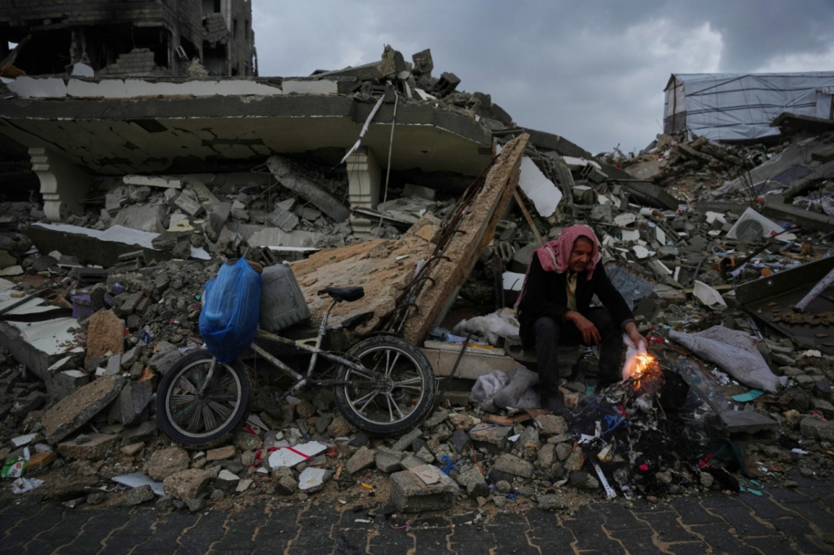 12일(현지시간) 가자지구 가자시티에서 한 팔레스타인 난민이 이스라엘의 공습과 지상 작전으로 파괴된 채 남아 있는 잔해에 앉아 불을 쬐고 있다. /AP=뉴시스 