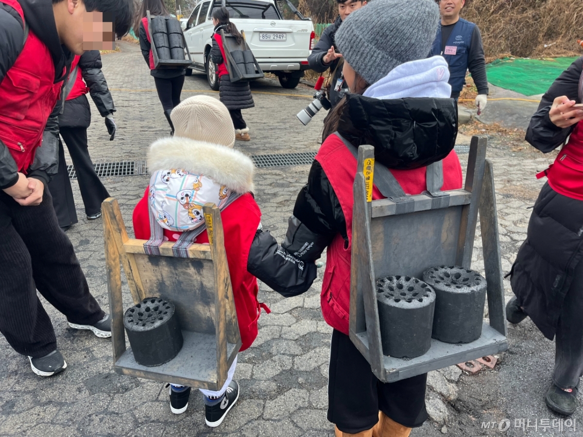 어린이 남매 봉사자가 연탄 지게를 메고 있다. /사진=이정우 기자.