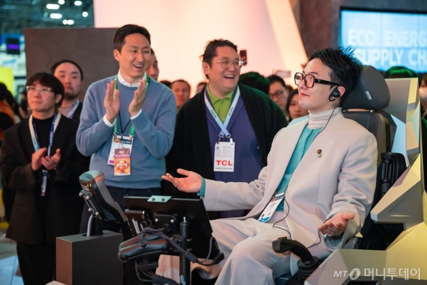 가수 지드래곤이 'CES 2024'의 HD현대 부스에서 '엑스에이전트' 기술 시뮬레이터에 탑승해 휠로더 조종 체험을 했다. 정기선 HD현대 부회장은 체험을 마친 지드래곤에게 박수를 보내고 있다. /사진제공=HD현대