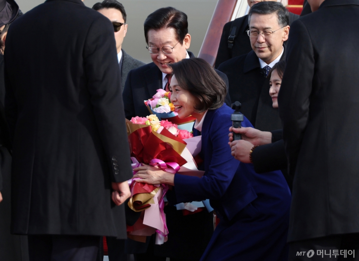 [베이징=뉴시스] 최동준 기자 = 이재명 대통령과함께 중국을 국빈 방문한 김혜경 여사가 4일(현지 시간) 베이징 서우두 국제공항에 도착해 꽃다발을 받고 있다. 2026.01.04. photocdj@newsis.com /사진=