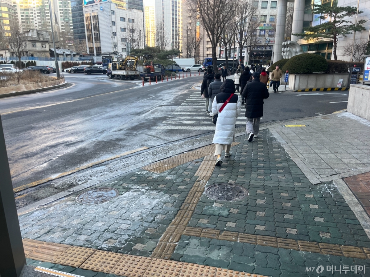 13일 오전 서울 마포구 공덕역 6번출구 앞 전날 내린 눈으로 형성된 빙판길 위를 시민들이 걷고 있다./사진=이정우 기자.
