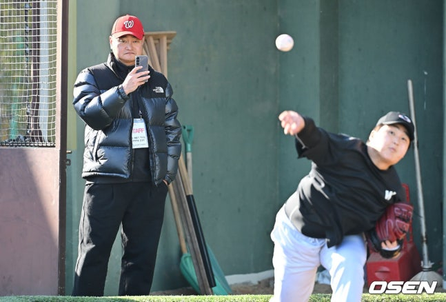 투구하는 선수의 동작을 영상으로 녹화하고 있는 박명환 투수코치(왼쪽).