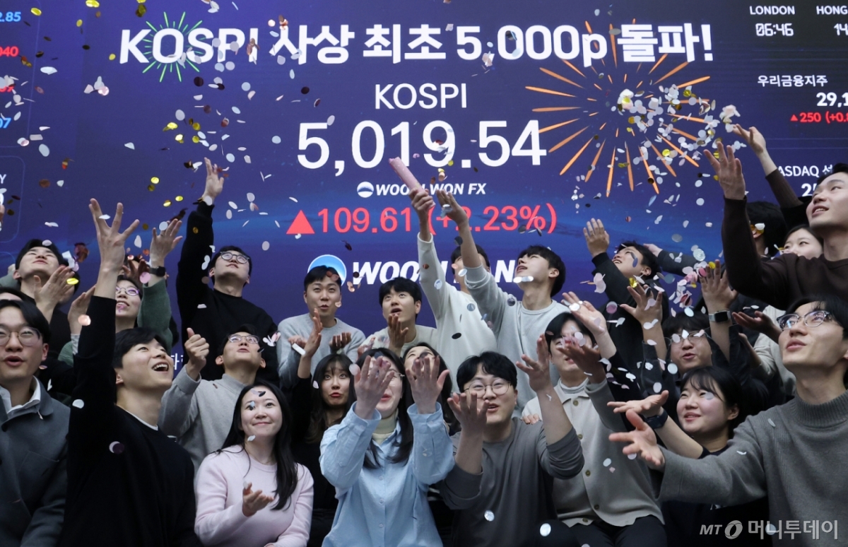 (서울=뉴스1) 오대일 기자 = 한국 증시가 사상 처음으로 '코스피 5000' 쾌거를 달성한 22일 서울 중구 우리은행 본점 딜링룸에서 직원들이 장중 최고가가 찍힌 전광판을 배경으로 코스피 5000 돌파를 축하하고 있다.   이날 코스피는 이재명 대통령이 '코스피 5000' 공약을 내걸고 임기를 시작한 지 7개월 만에 장중 꿈의 5000을 돌파하며 한국 자본시장의 역사를 새로 썼다. 2026.1.22/뉴스1  Copyright © 뉴스1. All rights reserved. 무단 전재 및 재배포,  AI학습 이용 금지. /사진=(서울=뉴스1) 오대일 기자