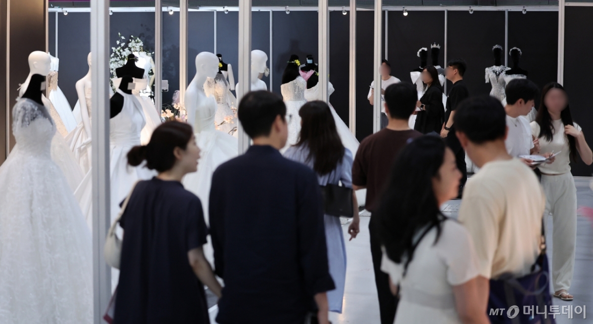 (서울=뉴스1) 김성진 기자 = 6일 서울 강남구 삼성동 코엑스에서 열린 2025 추계 웨덱스 웨딩 박람회에서 예비 부부들이 전시된 드레스를 살펴보고 있다. 2025.7.6/뉴스1  Copyright © 뉴스1. All rights reserved. 무단 전재 및 재배포,  AI학습 이용 금지. /사진=(서울=뉴스1) 김성진 기자