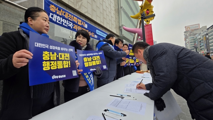 ▲지난 1월 15일 충남 천안시 동남구 신부동 신세계백화점 앞에서 열린 더불어민주당 충남도당 ‘충남대전 행정통합 서명운동본부’ 발대식에서 통합에 찬성하는 한 시민이 서명하고 있다./사진=뉴스1