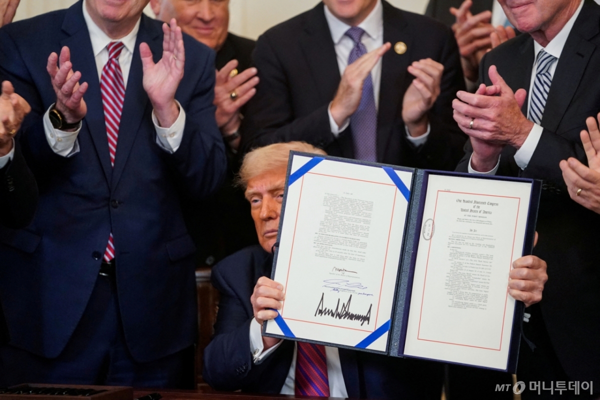 (워싱턴DC 로이터=뉴스1) 류정민 특파원 = 도널드 트럼프 미국 대통령이 18일(현지시간) 워싱턴DC 백악관에서 서명한 '지니어스 법안'(Genius Act, Guiding and Establishing National Innovation for U.S. Stablecoins Act)을 들어 보이고 있다. 지니어스 법안은 디지털 자산인 스테이블코인을 제도화하기 위해 연방 정부 차원의 규제 프레임워크를 개발하고 업계 감독을 확대하는 등의 내용을 담고 있다. 2025.07.18 ⓒ 로이터=뉴스1 Copyright © 뉴스1. All rights reserved. 무단 전재 및 재배포, AI학습 이용 금지. /사진=(워싱턴DC 로이터=뉴스1) 류정민 특파원