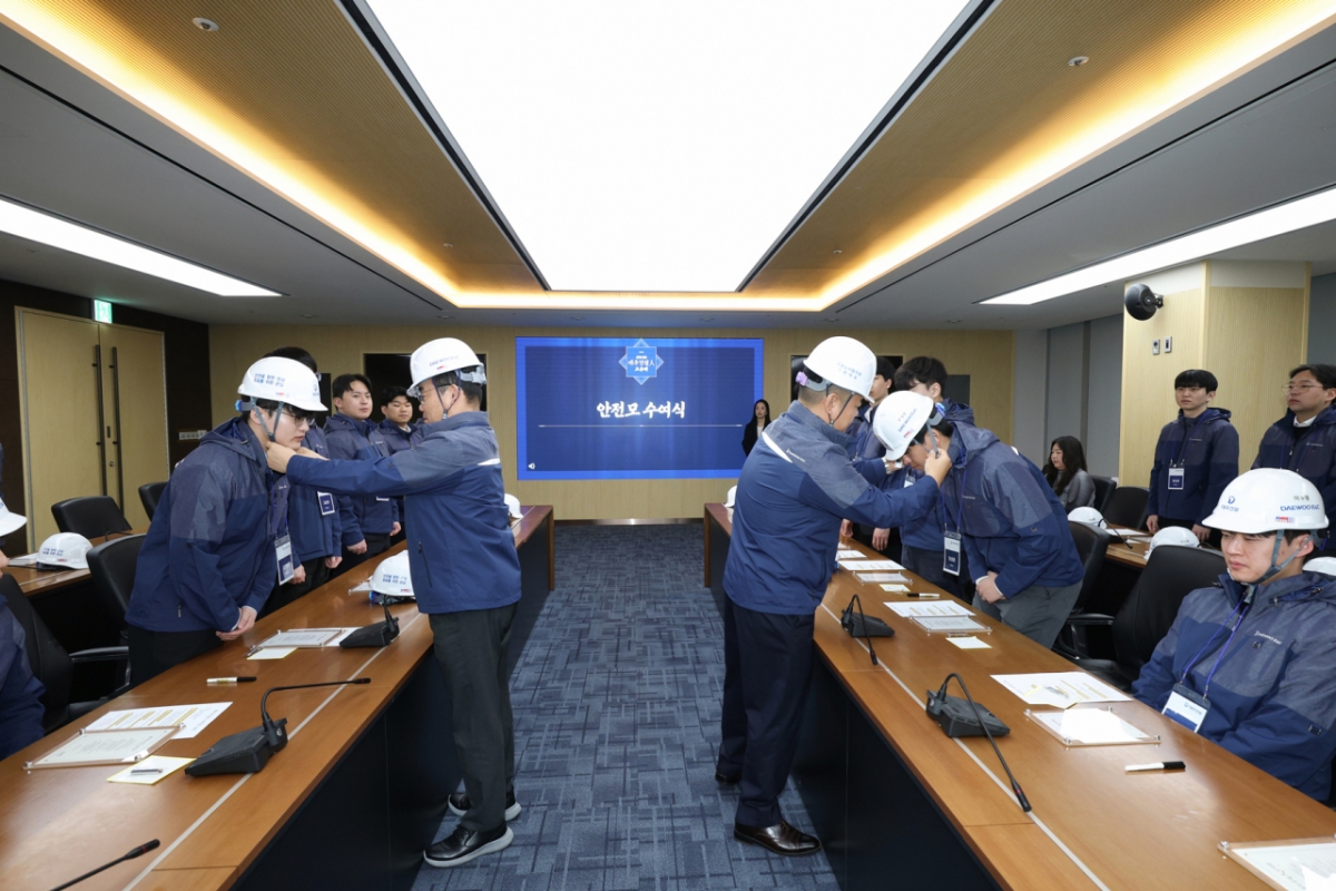 김보현 대표이사(왼쪽)와 심상철 노동조합 위원장(오른쪽)이 신입사원에게 안전모를 씌워주고 있다./사진제공=두산건설