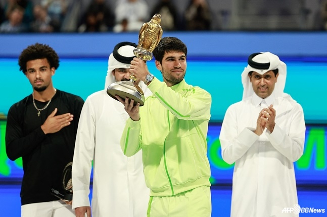 카를로스 알카라스(형광색 상의)가 트로피를 들고 미소짓고 있다. /AFPBBNews=뉴스1