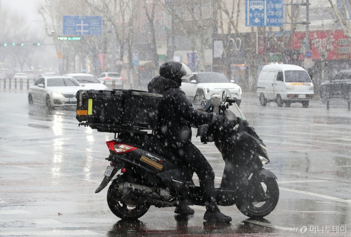 (대구=뉴스1) 공정식 기자 = 24일 오후 대구 수성구 대구은행네거리 인근에 갑작스레 많은 눈이 내리는 가운데 배달 라이더가 신호 대기 중 눈을 맞고 있다. 2026.2.24/뉴스1 Copyright © 뉴스1. All rights reserved. 무단 전재 및 재배포, AI학습 이용 금지. /사진=(대구=뉴스1) 공정식 기자